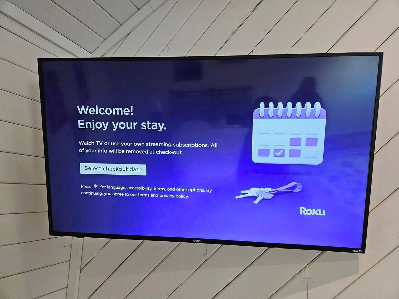 Una pantalla de televisión muestra un mensaje de bienvenida para el servicio Roku TV, con opciones para seleccionar una fecha de salida y acceder a los términos y la política de privacidad.