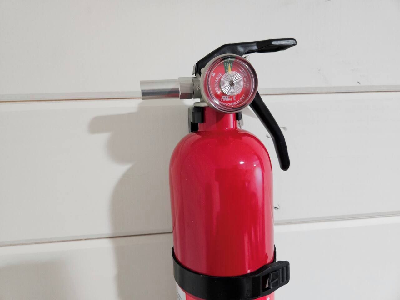 A red fire extinguisher mounted on a white wall.