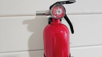 A red fire extinguisher mounted on a white wall.