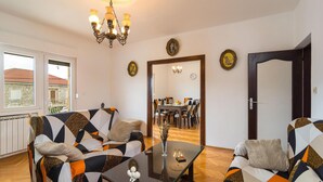 A living room with a sofa, armchairs, a glass coffee table, and a dining area in the background. - Beautiful apartment in Gornje Selo with WiFi (Gornje Selo)