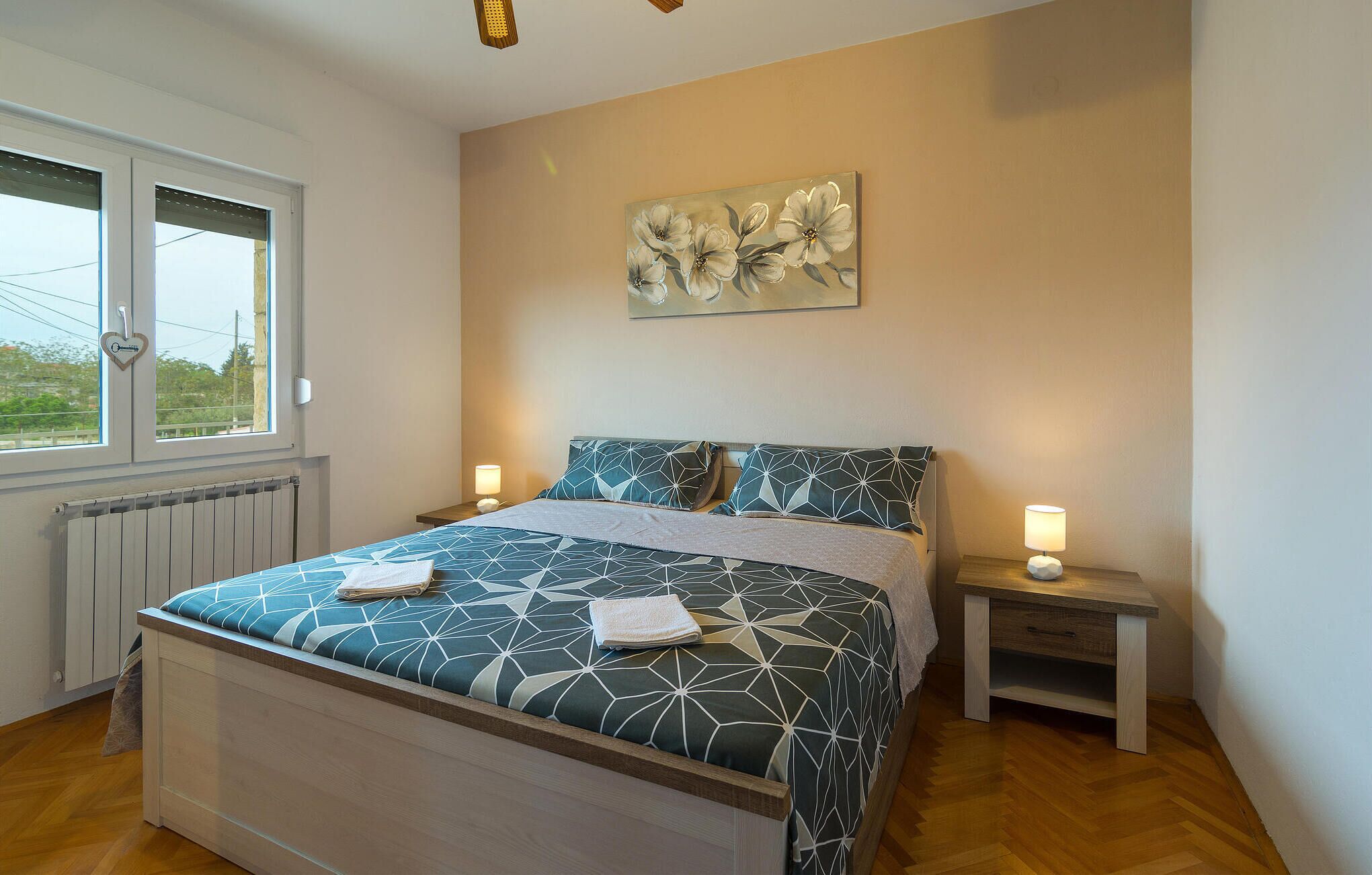 Ein Schlafzimmer mit einem Bett, zwei Nachttischen, einem Heizkörper und einem Fenster.