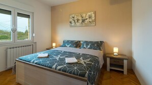 A bedroom with a bed, two bedside tables, a radiator, and a window. - Beautiful apartment in Gornje Selo with WiFi (Gornje Selo)