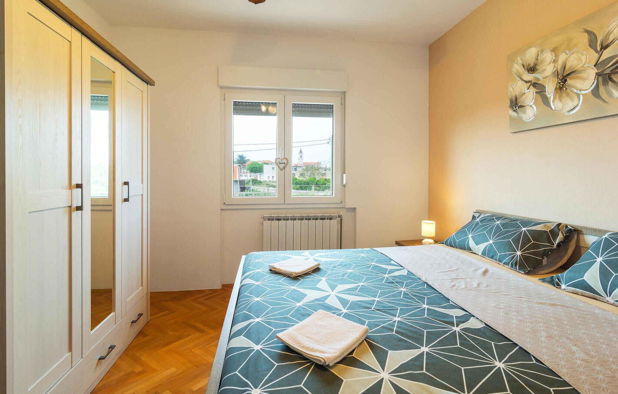 Um quarto com uma cama, uma janela, um radiador e um guarda-roupa.