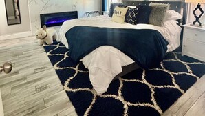 Une chambre à coucher comprenant un lit, un ventilateur de plafond, une télévision, des œuvres d’art accrochées au mur et une table de chevet avec une lampe.