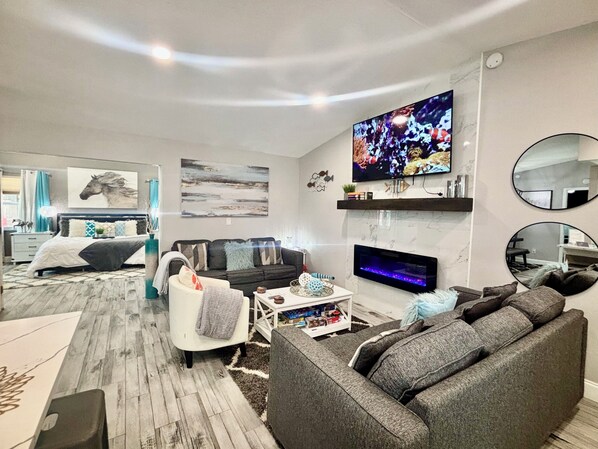 A modern living room with a flat-screen TV, a fireplace, and a large mirror.