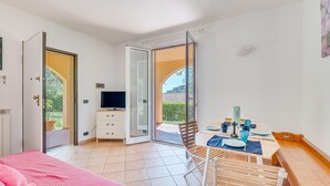 A bedroom with a bed, a TV, a desk, and a dining area with a table and chairs. - Beautiful home in Diano Calderina (Diano Calderina)