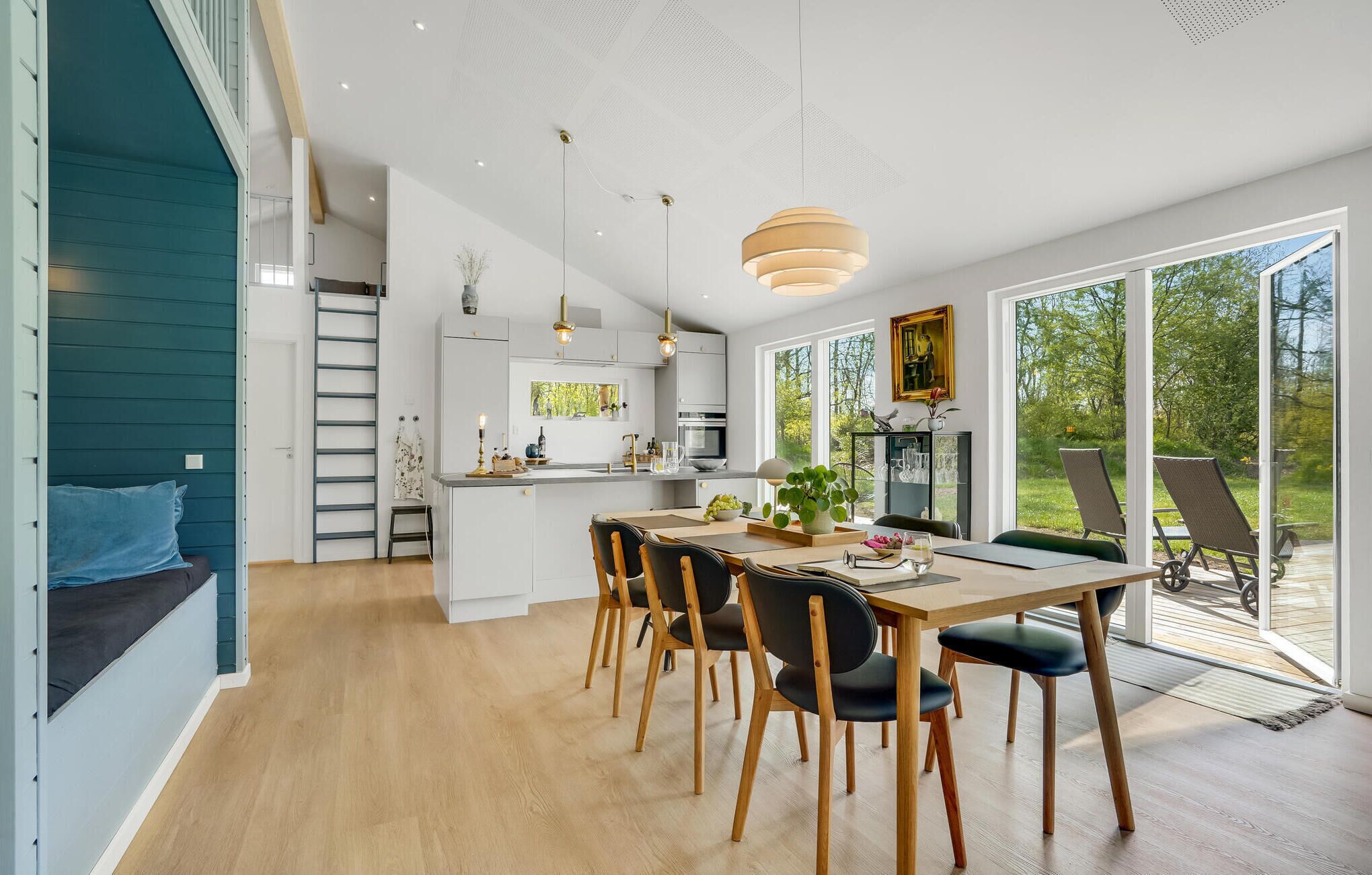 A modern kitchen with white cabinets, a dining area with wooden chairs, and a large sliding glass door leading to an outdoor deck.