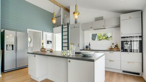 Eine moderne Küche mit weißen Schränken, einer zentralen Kochinsel und einem eingebauten Backofen.