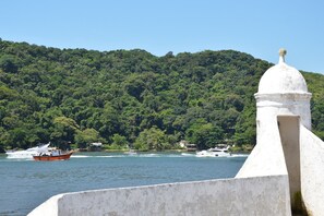 Vista sulla costa con una barca sull'acqua e un edificio bianco con una struttura a cupola.