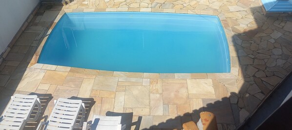 Una piscina rettangolare con un bordo pavimentato in pietra.
