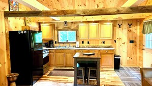 Interior em madeira com cozinha, incluindo frigorífico, fogão e armários de madeira.