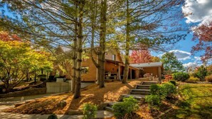 A wooden cabin with a stone staircase leading to the entrance, surrounded by trees and a well-maintained garden.