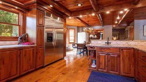 A spacious kitchen with wooden cabinets, a stainless steel refrigerator, and a large island with a sink.