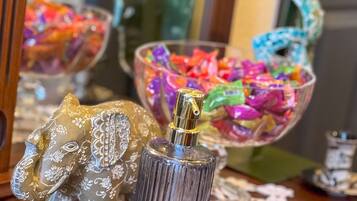 A wooden table with a decorative elephant figurine, a glass perfume bottle, and two glass bowls filled with colorful candies.