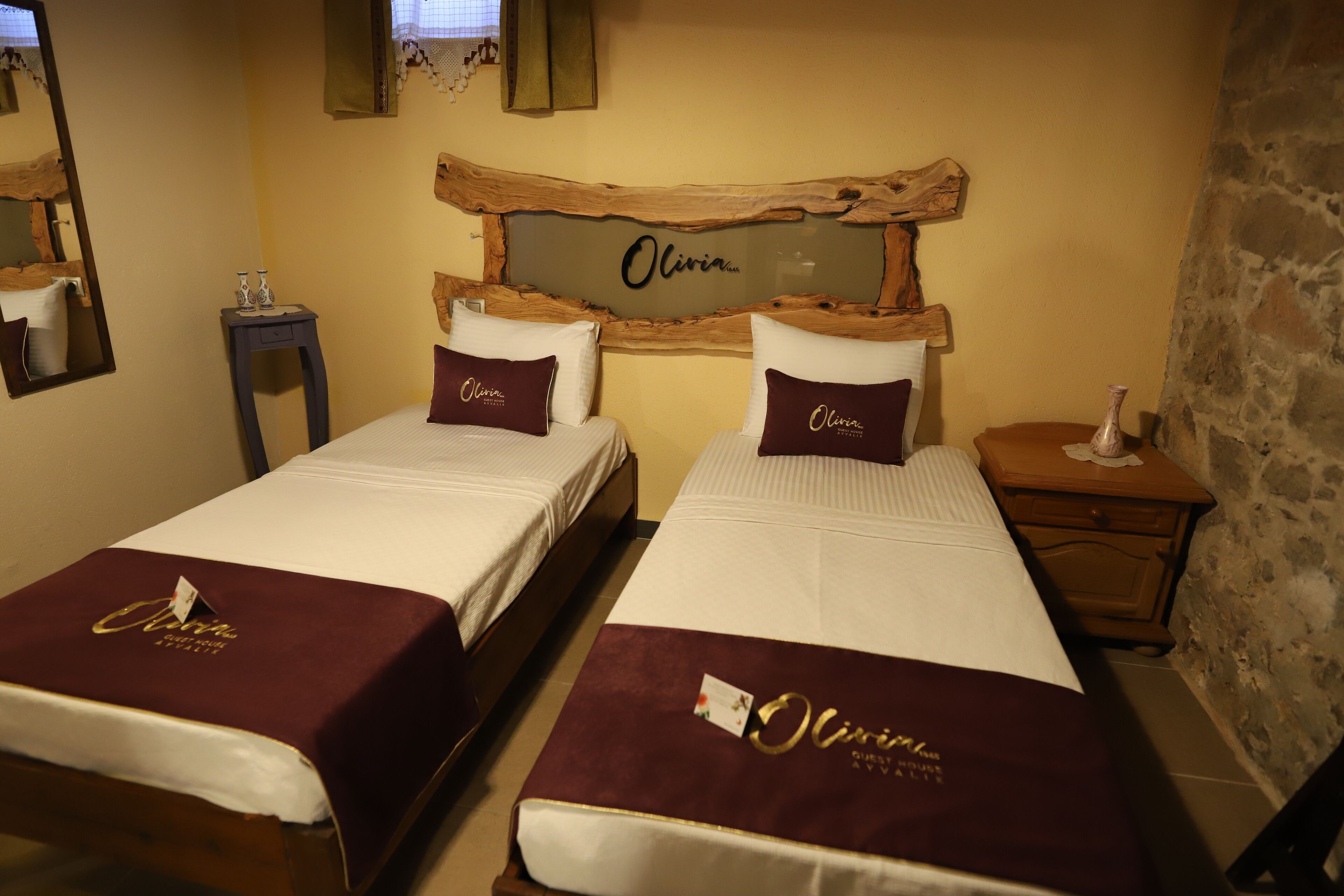 Een hotelkamer met twee bedden, elk met een bijpassend hoofdeinde en kussen, en een houten decoratie aan de muur erboven.