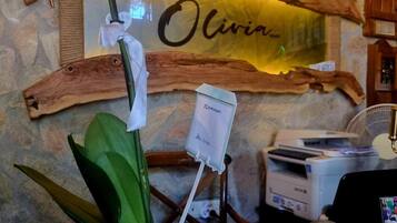 Una recepción con una orquídea en maceta, un letrero de madera con el nombre 'Olivia', un calendario que indica '16 de junio' y una impresora.