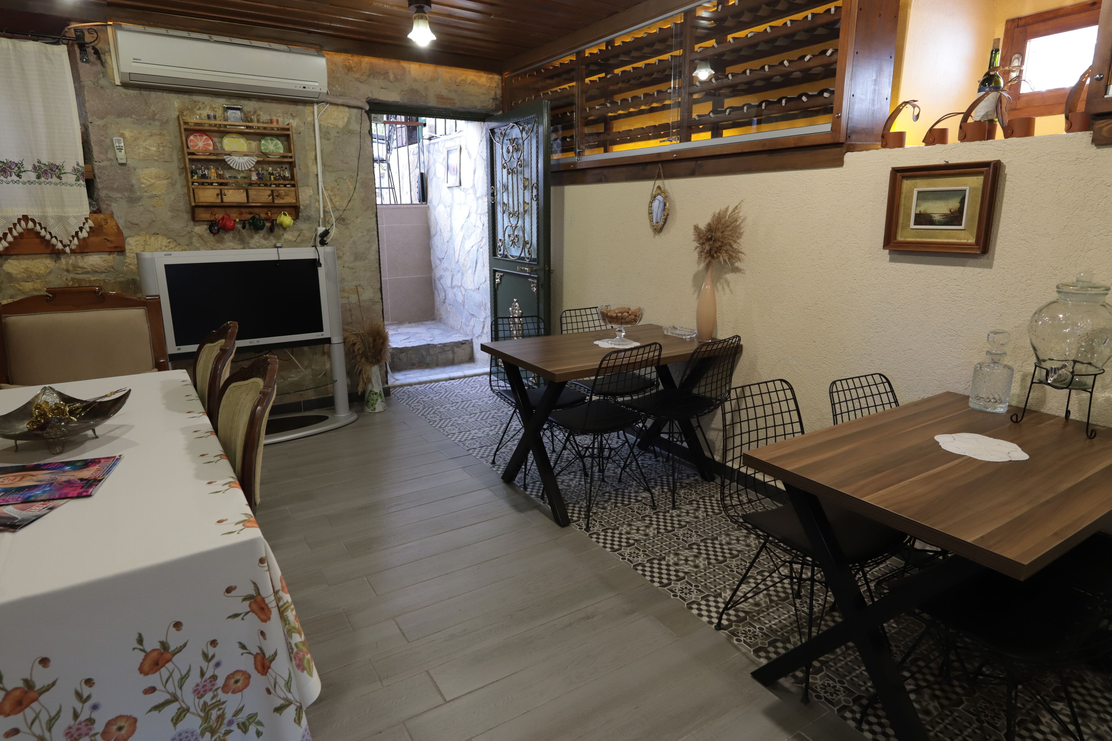 Un coin repas avec une table et des chaises en bois, un téléviseur et un meuble à bouteilles.