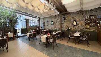 Ein Restaurant mit Steinwänden, Holzmöbeln und verschiedenen Tischgestaltungen.