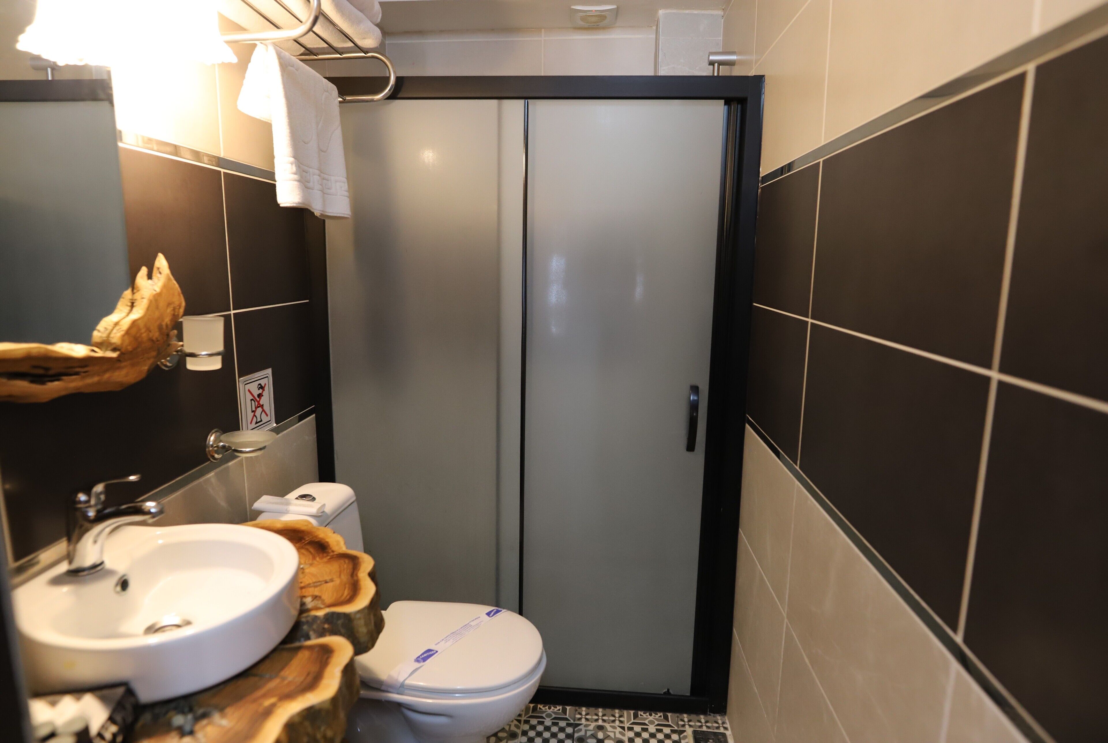 Ein kleines Badezimmer mit einem weißen Waschbecken, einer Toilette und einer Milchglas-Tür.