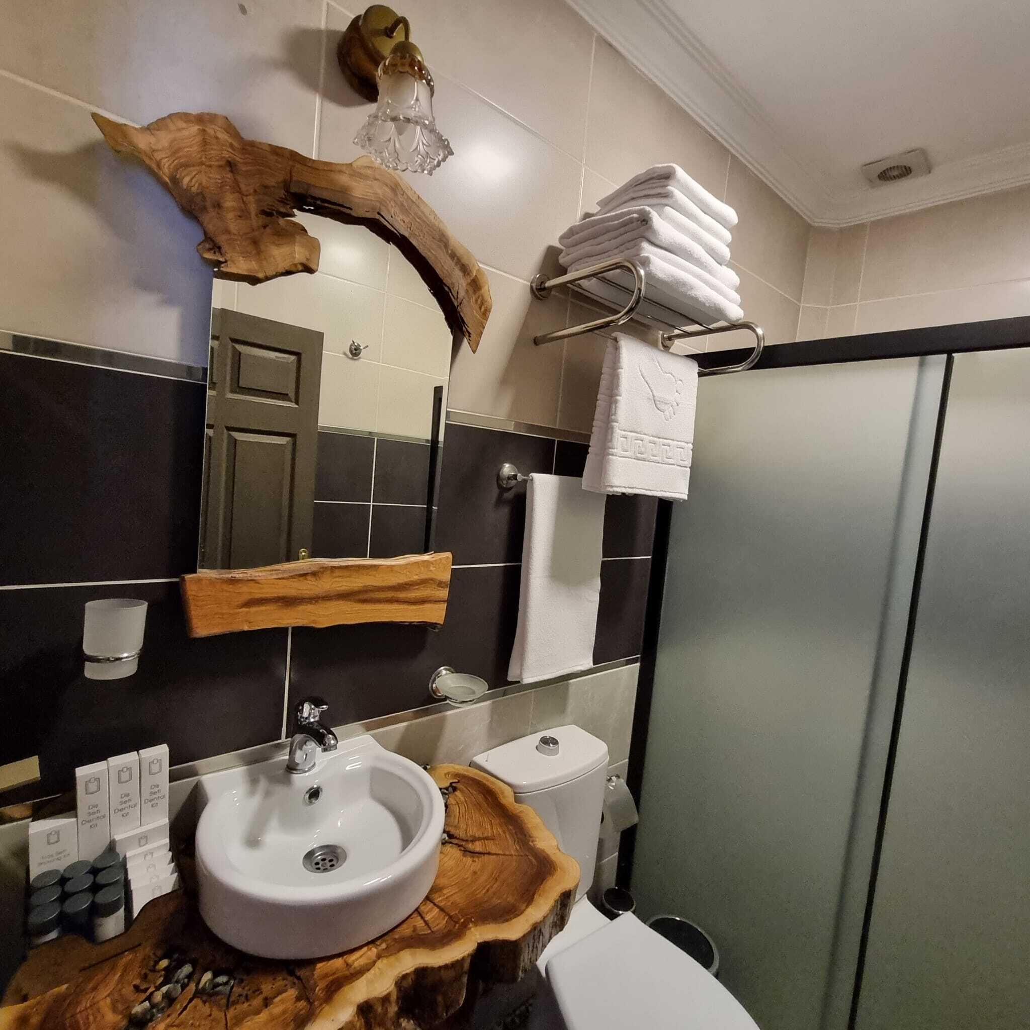 A modern bathroom with a wooden vanity, a sink, a toilet, and a mirror.