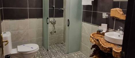 A bathroom with a glass-enclosed shower, a toilet, and a sink with a wooden countertop.