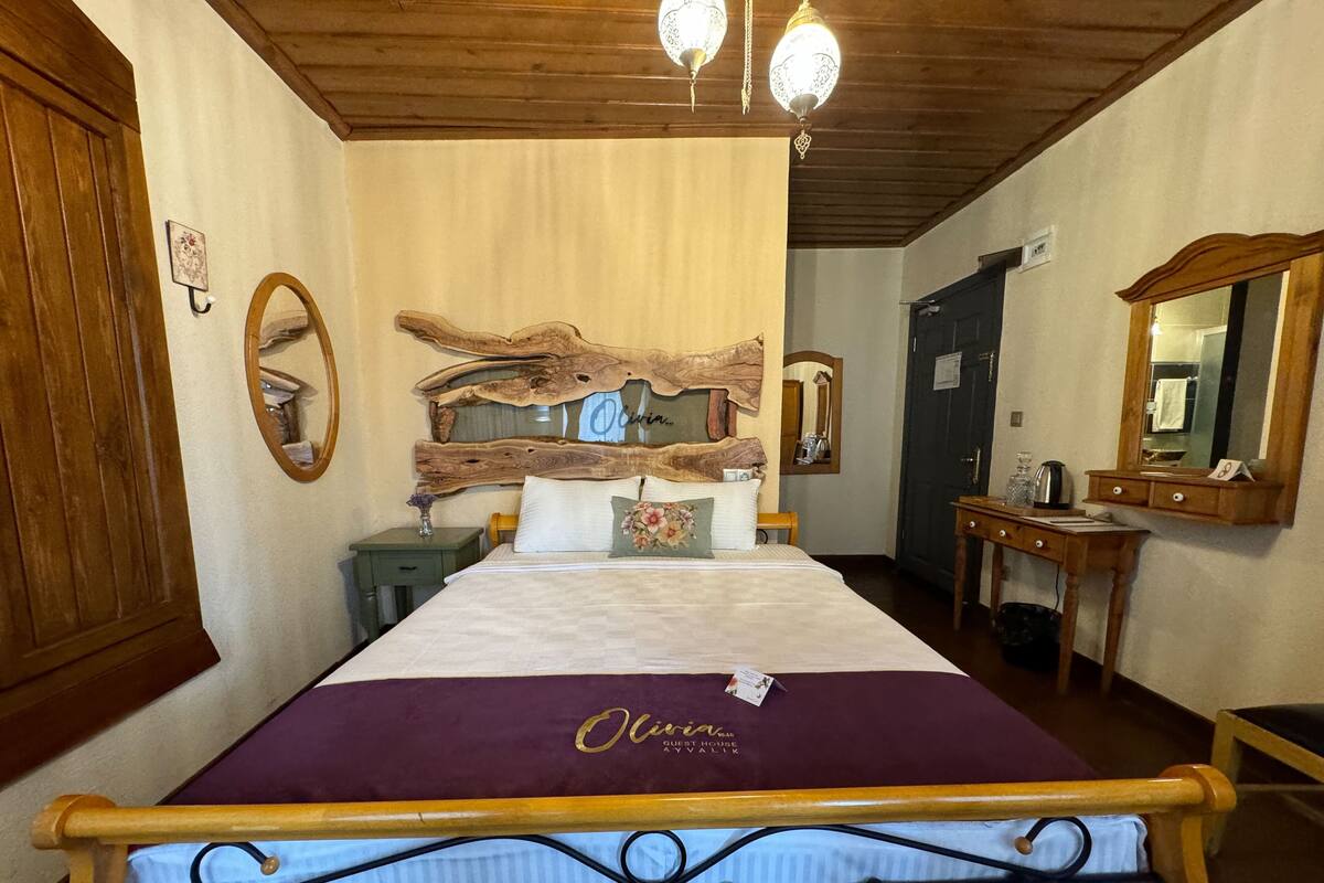 Een slaapkamer met een groot bed, een houten hoofdbord, twee nachtkastjes, een kaptafel en een spiegel.