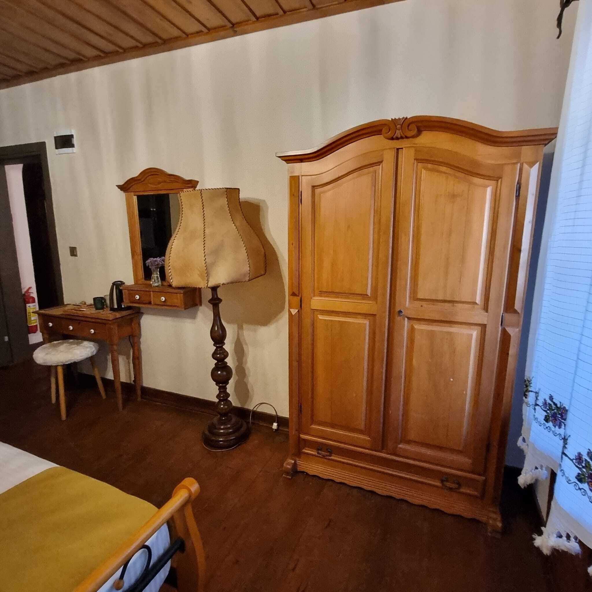 Une pièce comprenant une armoire en bois, un bureau avec une lampe, une chaise et un lit.