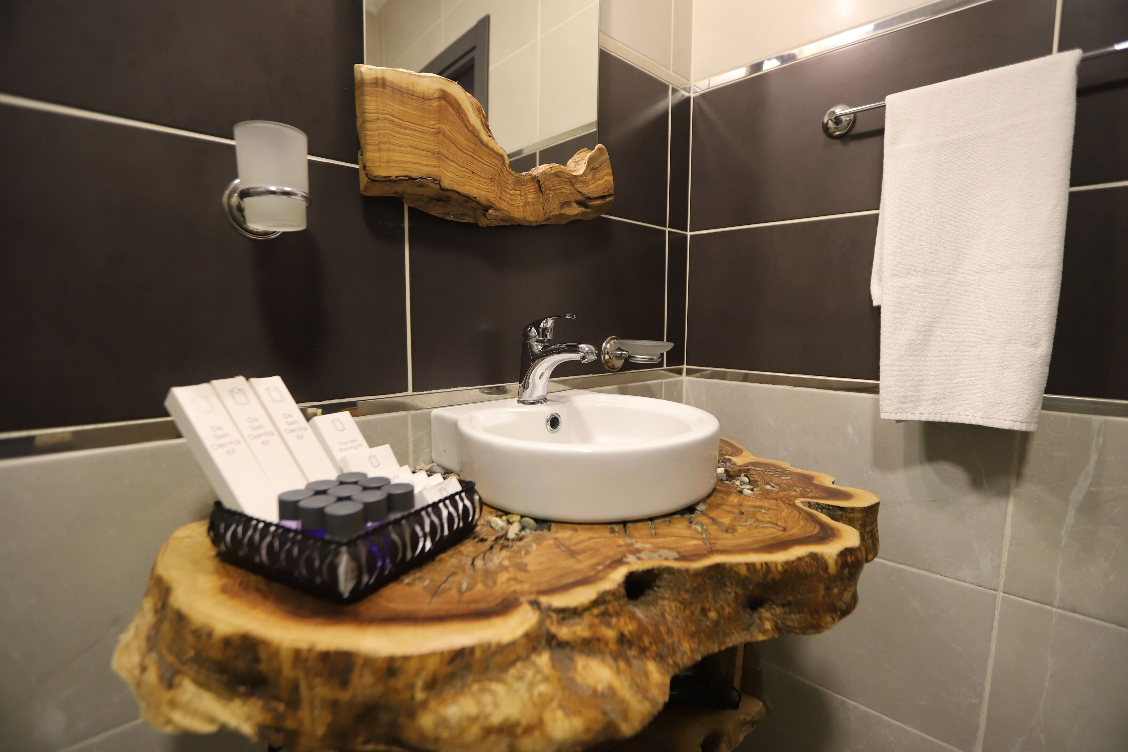 A bathroom with a wooden vanity, a white sink, and a towel hanging on a rack.