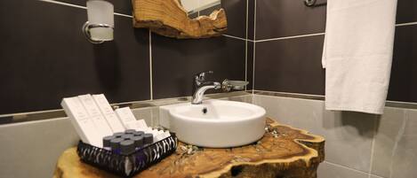 A bathroom with a wooden vanity, a white sink, and a towel hanging on a rack.