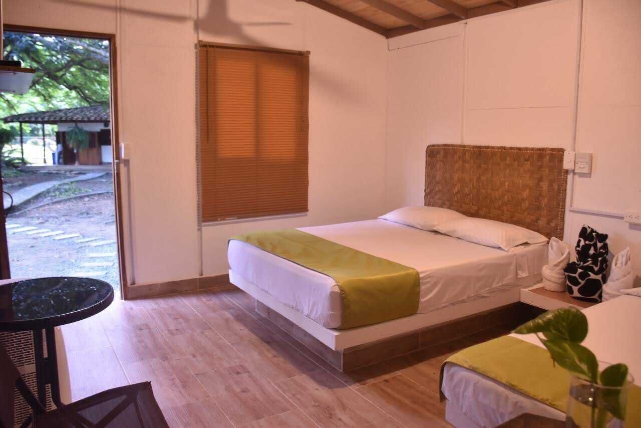 A bedroom with a bed, a small table, and a window with blinds.