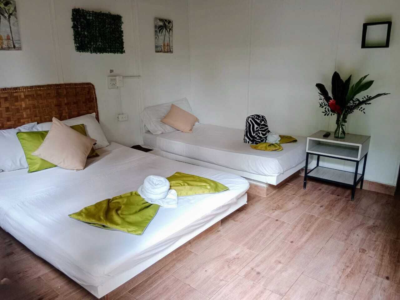 Een hotelkamer met twee enkele bedden, een klein nachtkastje en een wandplank.