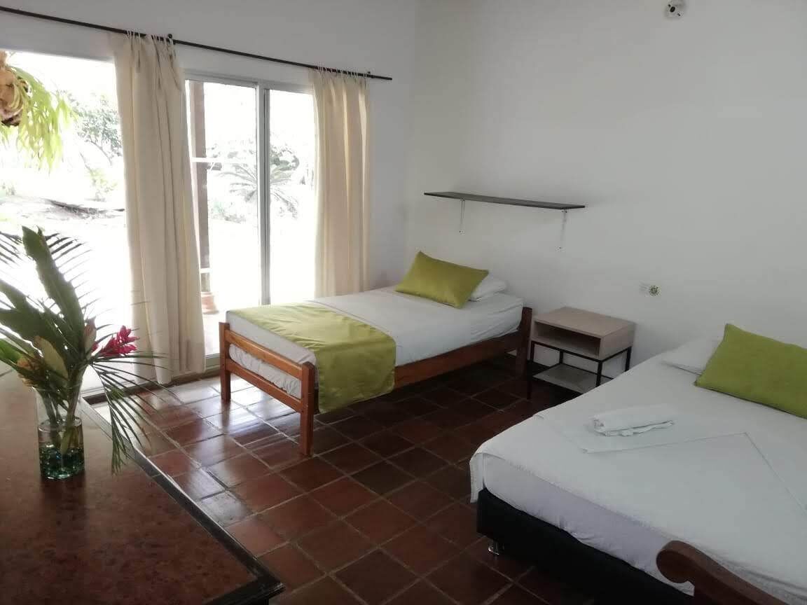 A room with two beds, a small table, and a shelf.