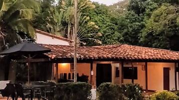 Una piscina con solárium de azulejos, una palmera y un edificio con tejado de cerámica.