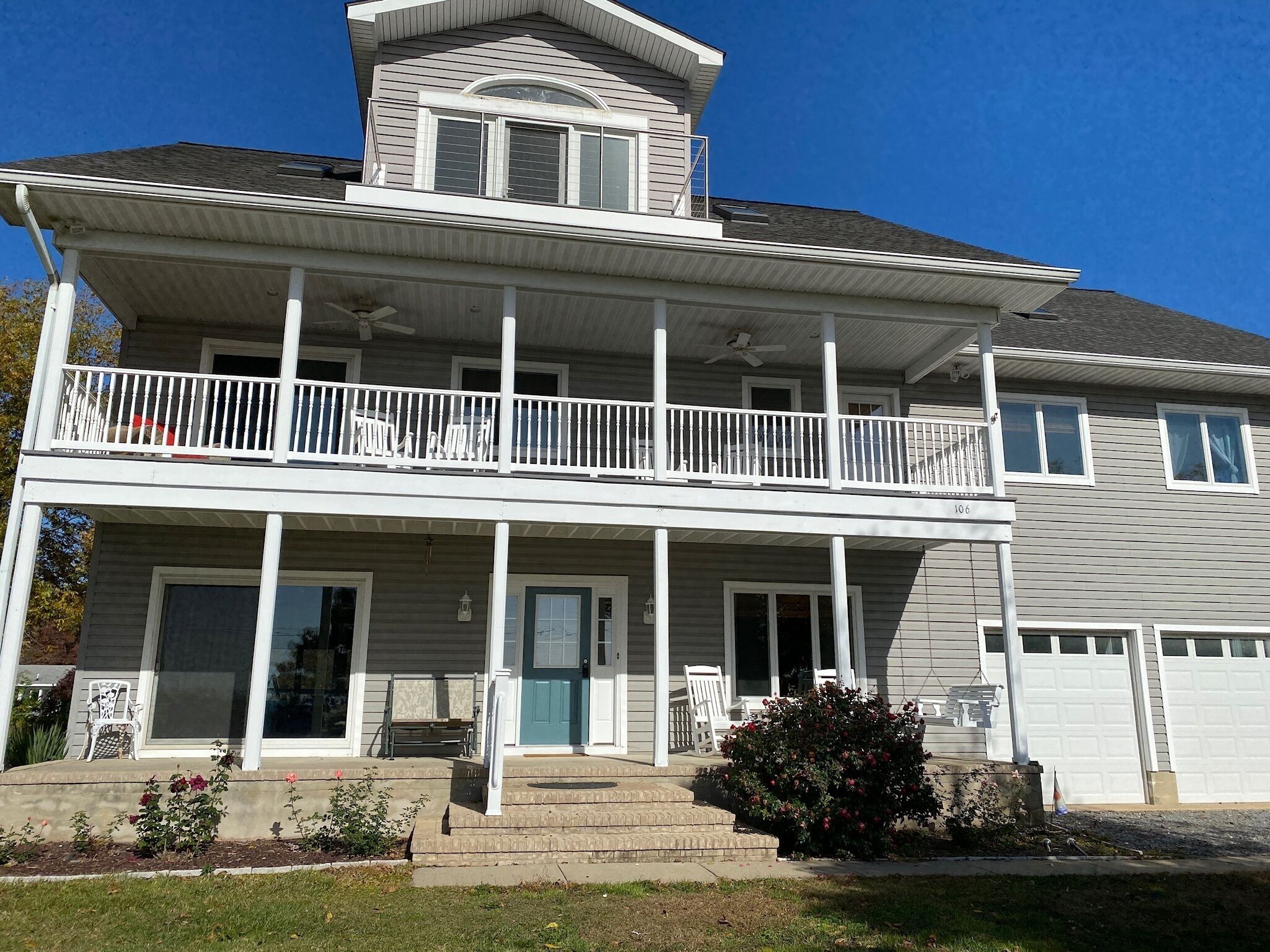 A two-story house with a balcony, a front porch, and a small tower-like structure on the roof.