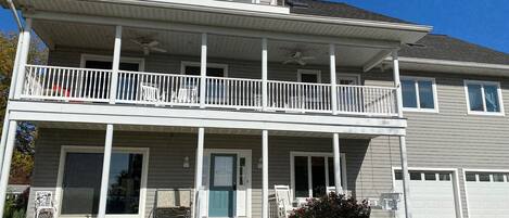 A two-story house with a balcony, a front porch, and a small tower-like structure on the roof.