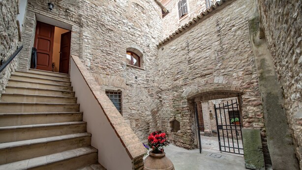 A stone staircase leading to a wooden door, a large stone wall, and a metal gate.
