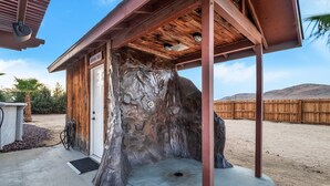 A rustic wooden building with a stone facade, a covered entrance, and a clear sky in the background.