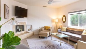 A modern living room with a fireplace, a sofa, a coffee table, and a television mounted on the wall.