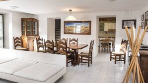 Ein modernes Wohnzimmer mit einem weißen Sofa, einem Holzespeisetisch, Stühlen, einem Holzschrank und einem Bild an der Wand.