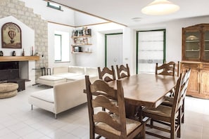 A dining area with a wooden table, chairs, a sofa, and a fireplace.