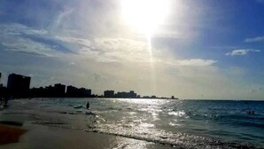 A beach with a clear sky and sunlight reflecting on the water.