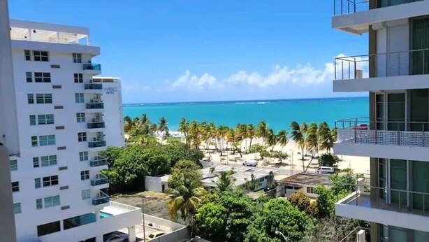 A hotel with multiple floors, a pool area, and a view of the beach and ocean.
