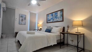 A hotel room with a bed, a nightstand, a lamp, and two paintings on the wall.