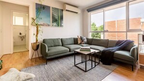 Uma sala de estar moderna com sofá seccional, mesa de centro e uma grande janela que oferece luz natural.