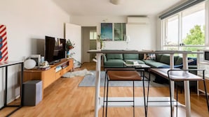 Uma sala de estar moderna com televisão, sofá e área de jantar.