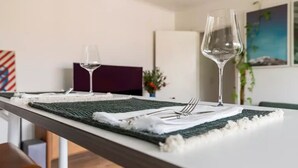 Mesa de jantar posta com jogo de toalha, taça de vinho e talheres.