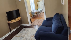 A living room with a TV, sofa, and a dining area in the background. - Salmo Hotel (Salmo)