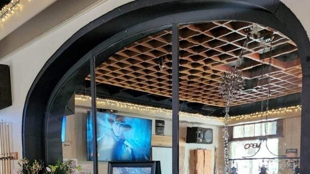 A bar area with a wooden counter, stools, and a large arched window. - Salmo Hotel (Salmo)