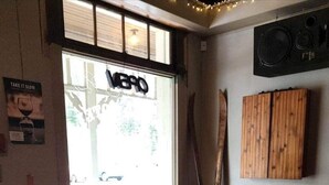 A cozy room with two leather armchairs, a small table with a lamp, a window with 'Take it slow' poster, and wooden paneling on the wall. - Salmo Hotel (Salmo)