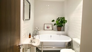 Un baño moderno con una bañera independiente, un inodoro y un lavamanos.